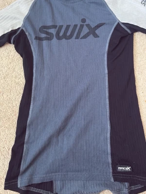 Swix blågrå funktions-tshirt S - Nypris 750!  (endast testad) Säljer en blågrå funktions-tshirt från Swix med svarta och ljusgrå paneler. Den är i storlek S.