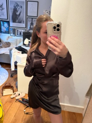 Mörkgrön satinklänning  - Snygg mörkgrön kort omlottklänning i satin med långärmad skjortkrage och lätt glansig finish.