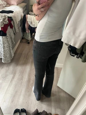 Svarta bootcut jeans med stretch - Säljer ett par svarta bootcut jeans med snygg passform och klassiska fickor både fram och bak. Jeansen har en lätt utsvängd benslut och är gjorda i stretchigt denimtyg för extra komfort. Perfekta för dig som gillar en tidlös och trendig look.