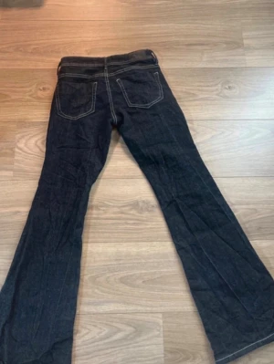 Mörkblå bootcut jeans med kontrastsömmar - Snygga mörkblå bootcut jeans med vita kontrastsömmar och klassiska fem fickor. Jeansen har låg midja och utsvängda ben. Dom är upplagda så de passar mig som är 160💕