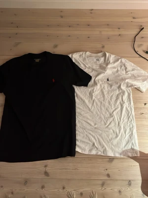 Svart och vit t-shirt från Ralph Lauren - Två klassiska t-shirts från Ralph Lauren, en svart och en vit, båda med den ikoniska broderade loggan på bröstet. T-shirtsen har rund hals och korta ärmar, tillverkade i mjuk bomull för en skön känsla. Har aldrig använt dem för att dem e för små för mig passar bäst 175-187 skriv om ni har några funderingar. Pris går att diskuteras