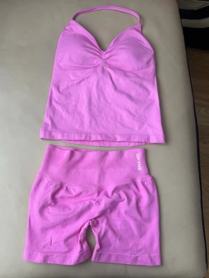Rosa seamless set från Define - Säljer ett rosa seamless set från Define med ett linne med smala axelband och lätt rynkning vid bysten samt matchande shorts med bred midjeresår. Setet är gjort i stretchigt material som sitter skönt mot kroppen. Perfekt för dig som gillar färgglada underkläder.