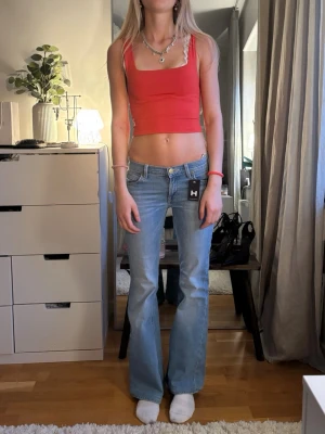 Röd croppad linnetopp - Trendig röd croppad linnetopp med breda axelband och fyrkantig ringning. Toppen är ärmlös och har en tight passform som framhäver midjan. Perfekt för att skapa en cool och avslappnad look.