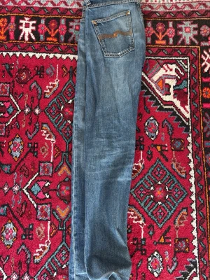 Blå slim fit jeans med slitningar - Snygga blå slim fit jeans med lätt slitna detaljer och klassisk femficksdesign. Jeansen har en medelhög midja och raka ben. Perfekta för en avslappnad och trendig look. Materialet är troligtvis bomullsdenim. Storlek 29 30