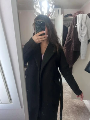 Kappa från vero Moda  - Storlek xs, tjock kappa som går att använda under vinterhalvåret. Den är lång och har fickor och ett snöre som man kan knyta till i midjan. Kappan är lite använd men fortfarande i bra skick 