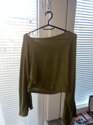 Olivgrön croppad långärmad topp, Gina Tricot - Trendig olivgrön croppad topp med lång ärm och lös passform. Tunt stickat material som ger en luftig känsla. Perfekt att styla med höga jeans eller kjol.