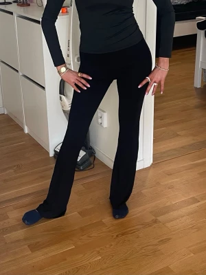 Svarta utsvängda leggings - Snygga svarta leggings med utsvängda ben och hög midja. Stretchigt material som sitter tajt över höfterna och låren och släpper ut vid vaden. Perfekta för en trendig och bekväm look.
