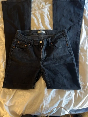 Hägmidjade svarta bootcut jeans  - Snygga svarta jeans från gina med klassisk femficksdesign och raka ben. Jeansen har en hög midja och är tillverkade i ett mjukt denimtyg med lite stretch. Perfekta för en stilren och avslappnad look.