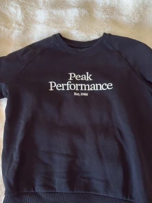 Svart sweatshirt från Peak Performance - Svart sweatshirt med vit broderad Peak Performance-logga på bröstet. Klassisk rund halsringning och ribbade muddar vid ärmslut och nederkant. Perfekt för en avslappnad och sportig stil. Skriv för frågor❤️