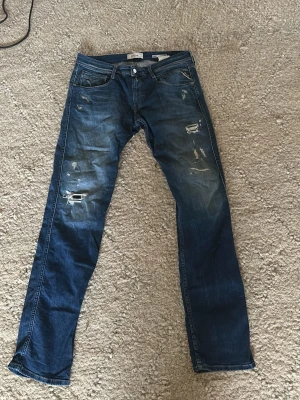 Blå slitna jeans med raka ben - Snygga blå jeans med slitningar och hål på låren och knäna. Jeansen har klassisk femficksdesign, låg midja och raka ben. Perfekta för en avslappnad streetstil. Materialet är denim i bomull. Storleken är w34 l34. Aldrig använda, super skick på den, nypris var 1299, 