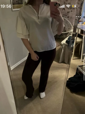 Vit blus med volangärmar - Säljer en vit blus med v-ringning och dragkedja framtill. Blusen har korta volangärmar i två lager som ger en cool och trendig look. Passar perfekt till både jeans och kjol. Materialet känns mjukt och lätt.