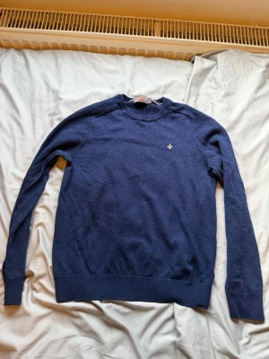 Morris merinoulltröja i mörkblå färg. Köpt i storlek XL men har krympt i tvätten och motsvarar nu ungefär S.  - En stilren mörkblå tröja med rund hals och diskret broderad logga på bröstet. Tröjan har långa ärmar och ribbade muddar vid ärmslut och nederkant. Perfekt för dig som gillar enkel och klassisk stil.