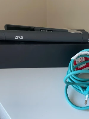 Lyko plattång  - Snygg och modern plattång från Lyko i matt grå färg med digital temperaturkontroll mellan 120°C och 220°C. Sladden är turkos och flexibel, vilket gör styling enkel. Perfekt för att skapa släta och glansiga frisyrer.