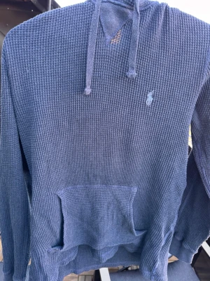 Blå stickad hoodie från Polo Ralph Lauren🙌🤩 - Säljer en blå hoodie från Polo Ralph Lauren med klassisk huva och dragsnören. Tröjan har ett strukturerat, våfflat tyg och en stor magficka framtill. Liten broderad logga på bröstet. Perfekt för en chill och avslappnad stil.🙌🤩