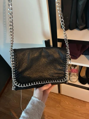 Svart axelväska med kedjerem - Mellanstolek jätte fin knappt använd, rymmer mycket och har flera fack inne i den, man kan göra om den så den får kortare band