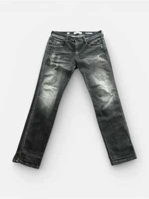 Replay - Säljer ett par grå jeans med slitningar och tvättade detaljer. Jeansen har raka ben, fem fickor och klassisk knappgylf. Perfekta för en avslappnad och trendig look. Använda 1/2 gånger.