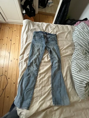 Blå bootcut jeans Abercrombie & Fitch - Säljer ett par ljusblå bootcut jeans från Abercrombie & Fitch. Jeansen har klassisk femficksdesign, snygga kontrastsömmar och en patch med logga bak i midjan. Tillverkade i mjuk denim med lätt slitning för en avslappnad look.