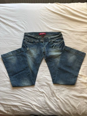 Blåa bootcut jeans  - Säljer ett par skitsnygga blåa bootcut jeans från Kenvelo med slitningar. Midja: 71cm Innerbenslängd: 76 cm Midjehöjd: 17cm