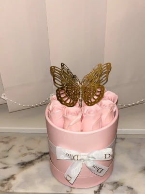 Evighetsrosor i söt presentbox - Säljer en lyxig rosa presentbox fylld med konstgjorda rosor och dekorerad med en guldfärgad fjäril och vitt lyxigt band 🎀 . Boxen är elegant inslagen. Passar helt Perfekt som gåva eller dekoration till hemmet. 