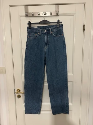Blå loose jeans från H&M - Klassiska blå jeans från H&M med loose passform och hög midja. Jeansen har fem fickor, knappgylf och är tillverkade i kraftig denim. Perfekta för en avslappnad och tidlös stil. Storlek 29/32