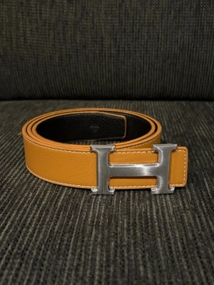 Brunt bälte - Ett brunt/orange bälte, få defekter. Gjort 1 eget hål så inte nyskick. 110 cm långt 