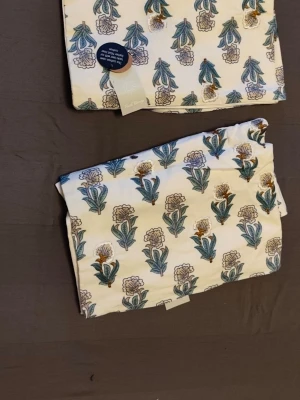 Kuddfodral Liza med blommigt mönster - Kuddfodral i bomull från KID/KEMTEX, modell Liza. Fodralet är vitt med broderat blommigt mönster i grönt, blått och gult. Perfekt för att ge soffan eller sängen en färgklick och en mysig känsla. Tillverkat i Indien och märkt med Better Cotton. 300:- för båda  värde 900:-