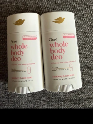 Dove Whole Body Deo Raspberry & Rose - Dove Whole Body Deo är en deodorantstick för hela kroppen med doft av hallon och ros. Passar känslig hud och är fri från aluminium. För armhålor, bröst, lår och intima områden. Vit plastförpackning med rosa text och guldlogga.