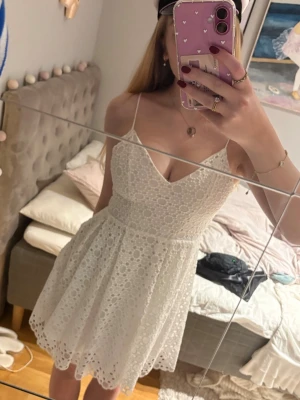 Vit spetsklänning  - Säljer en vit klänning med smala axelband och v-ringning. Klänningen är från H&M i storlek 36 och har ”spets” detaljer. Perfekt sommarklänning eller till studenten.