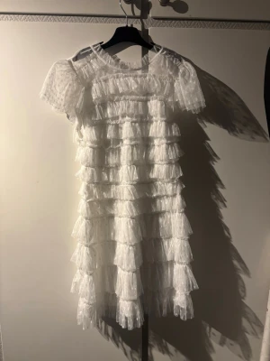 Bubbleroom klänning vit - Supersöt vit kortklänning med flera lager volanger och spetsdetaljer. Klänningen har korta ärmar och en luftig, romantisk look som verkligen sticker ut. Perfekt för dig som vill ha något extra till sommaren eller speciella tillfällen. Aldrig använd