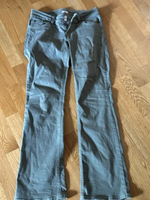 Gröna bootcut jeans från Nelly - Snygga gröna bootcut jeans från Nelly med klassisk femficksdesign och dubbla knappar i midjan. Jeansen har dragkedjegylf och är tillverkade i ett mjukt bomullsmaterial med lite stretch för extra komfort.