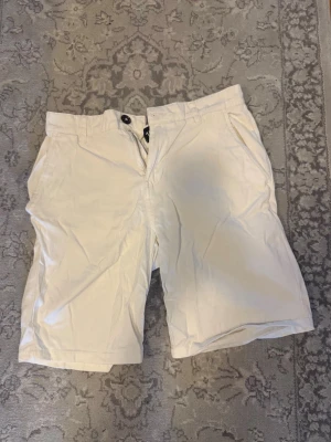 Vita shorts med knappar - Vita shorts med normal passform och knappar både fram och bakfickor. Klassisk design med bälteshällor och raka ben. Aldrig använda i storlek S