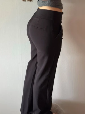 Svarta kostymbyxor midwaist - Säljer ett par svarta kostymbyxor från madlady med midwaist och raka ben. Byxorna har fickor fram och dekorfickor bak. Storlek 36 längd regular.  Jag är 165cm.