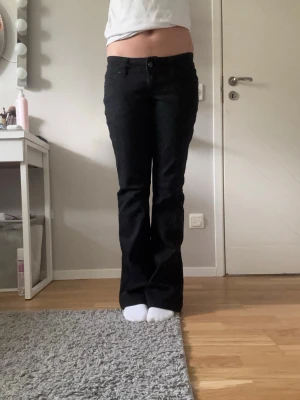 Svarta bootcut jeans - Säljer ett par svarta bootcut jeans med klassisk femficksdesign och normal midja. Jeansen har en snygg utsvängd passform nertill och stängs med knapp och dragkedja. Perfekta för dig som gillar en stilren och tidlös look. Köpta för 1000kr, säljer för 800 priset går att dissekera😊