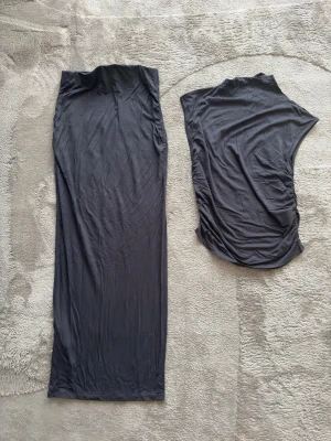 Svart set från Gina Tricot - Säljer en svart från Gina Tricot i mjuk bomull. Klänningen har en enkel och rak passform med ärmlös design, perfekt för en stilren look. Materialet är stretchigt och bekvämt, vilket gör den lätt att bära hela dagen.