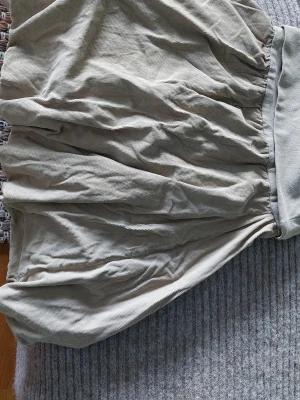 Beige kortkjol med resårmidja - Säljer en beige kortkjol med resår i midjan. Kjolen har en luftig och lite puffig form som ger en avslappnad vibe. Perfekt att matcha med en enkel topp eller hoodie.