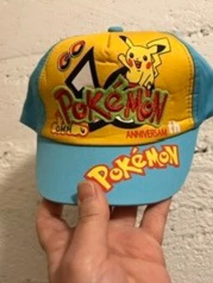 Pokémon keps med Pikachu-motiv - Färgglad keps med Pokémon-tema och Pikachu på framsidan. Kepsen är gul och ljusblå med tryck av Pokémon-loggan och jubileumstext. Justerbar baktill och tillverkad i bomullsmaterial. Perfekt för dig som älskar Pokémon och vill sticka ut. Helt ny , finns olika färger kvar 