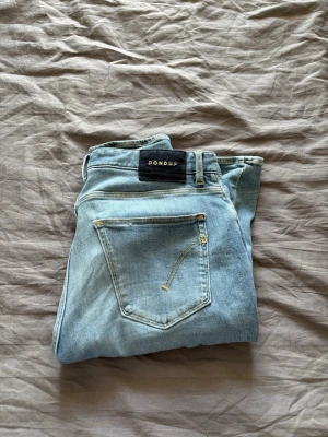 Dondup jeans - Snygga ljusblå jeans från Dondup med knappgylf. Jeansen är tillverkade i mjuk denim. Perfekta för en trendig och avslappnad look. Jag säljer dessa då jag vill ha nya. Storleken är 34 men passar också 32. Priset går att diskutera vid snabb affär 😊
