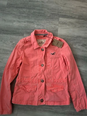 Korallfärgad jeansjacka från Hollister - Fin rosa jeansjacka från Hollister, köpte från Sellpy men var tyvärr lite liten. Jackan är lite mindre i storleken men väldigt fin. 