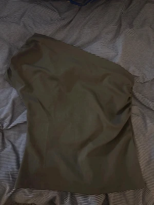 Mörkgrön oneshoulder topp - Snygg mörkgrön oneshoulder topp med enkel och stilren design. Toppen är axelbandslös på ena sidan och har en rak passform som sitter bekvämt. Perfekt för dig som vill ha en trendig och minimalistisk look.