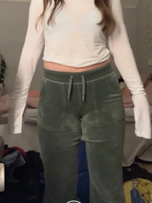 Juicy Couture byxor – Mörkgröna, Fint skick - Trendiga Juicy Couture-byxor i mörkgrönt – bekväma, stilrena och perfekta för både vardag och mys. Färgen ger en snygg twist jämfört med de vanliga svarta/gråa och är lätt att matcha med neutrala toner.Fint skick, lite avklippta längst ned( se sista bilden ). Jag är 165cm ungefär och de sitter bra på mig. Jag är för övrigt vanligtvis en S och byxorna sitter bra på mig. Så byxorna passar nog xxs, xs och S 