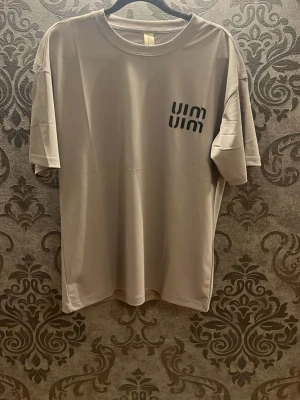 Två t-shirts från MIUMIU - Säljer två stilrena t-shirts från UIN, en i ljusgrått med svart logga och en i mörklila med vit logga. Båda har rund hals, korta ärmar och är gjorda i mjukt polyester-material. Perfekta för dig som gillar enkel och modern design.