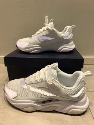  B22 skor - Säljer ett par vita  B22 sneakers med chunky sula och reflekterande detaljer. Skorna har mesh och läderpaneler, samt tydlig B22-logga på sidan. Snygg och modern design som sticker ut, perfekt för dig som gillar exklusiva sneakers. Säljer skorna då jag köpte en storlek för stor!! Pris kan diskuteras och våga skriva!!!