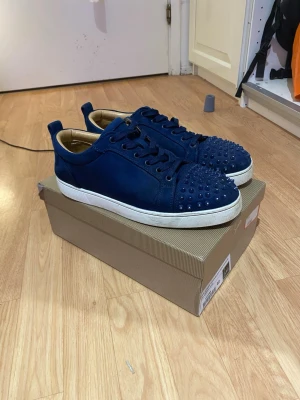 Blå Christian Louboutin sneakers - Säljer nu dessa snygga Christian Louboutin skorna i storlek 43,  de är använda och i 8/10 skick men går lätt att bli nästan som nya ifall du gör rent dom, låda, kvitto, extra spikar och alla andra saker som kommer med skorna finns och pris går att diskutera, hör av er vid frågor osv 💫