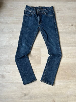 Blåa Thin Finn Nudie Jeans W29 L32 - Fina Nudie Jeans i mörkblå färg. Jeansen är i mycket bra skick och sparsamt använda. |  Äkta som allt annat jag säljer! ✅|  Storlek: W29 L32 | Skick: Mycket Bra Skick | Färg: Blå | Märke: Nudie | Modell: Jeans  |  Hör gärna av dig vid frågor så svarar jag så fort jag kan! 😁|   SKU - 2 |