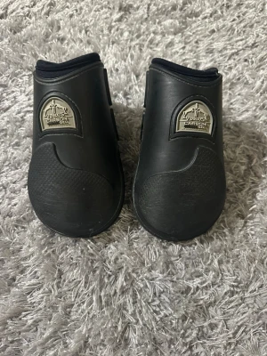 Svarta benskydd till häst Veredus - Säljer ett par svarta benskydd till häst från Veredus, modell Carbon Gel. De har dubbla spännen och är tillverkade i slitstarkt material med förstärkt yta framtill. Perfekta för träning eller tävling inom ridsport. Mycket bra skick, lite repiga men annars inga defekter. Hör av er vid frågor och kom gärna med prisförslag!💞