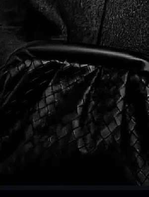 Svart flätad handväska - Snygg svart handväska med flätad design och mjukt, glansigt material. Väskan har en rundad form och bred kant upptill, vilket ger en modern och trendig look. Perfekt accessoar för dig som gillar stilrena detaljer.