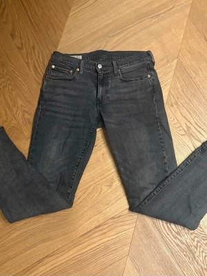 Svarta Levi's 501 jeans - Snygga svarta jeans från Levi's i klassisk femficksmodell. Jeansen är tillverkade i ett mjukt denimtyg med lätt stretch. Perfekta för dig som gillar en stilren och tidlös look.