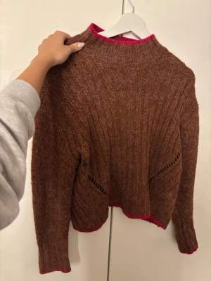 Brun stickad tröja med rosa detaljer - Så cool brun stickad tröja med neon/rosa detaljer på ärmarna, från okänt märke (se sista bild) i strl S men passar en xs-m