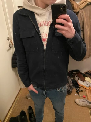 Mörkblå overshirt från Studio Total - Säljer en mörkblå overshirt från Studio Total. Jackan har dragkedja framtill, två bröstfickor med lock och klassisk krage. Materialet är kraftigt och ger en stilren look som passar till jeans och hoodie.