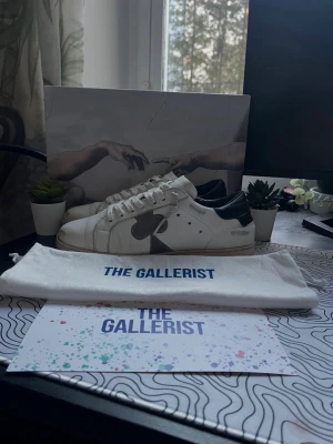 The Gallerist - Ett par svin snygga vita skor från The Gallerist med svarta svarta detaljer på hälen och sidorna. Nypris är 2699kr. Det är väldigt fint skick på skorna, dem har inga hål eller liknande.Modellen heter Geneva. Allt medföljer. Skorna är i storlek 39! Jag skickar samma dag! Hör av er!🙌